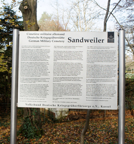 Photograph of sign at entrance to Sandweiler German War Cemetery with message for peace in three languages.